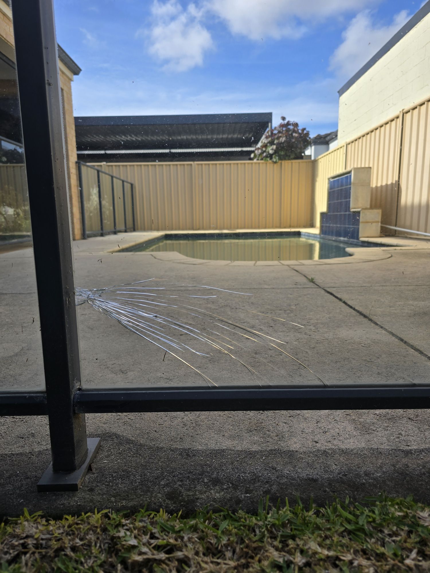 Close-up photograph of damage to the pool-fence glass panel